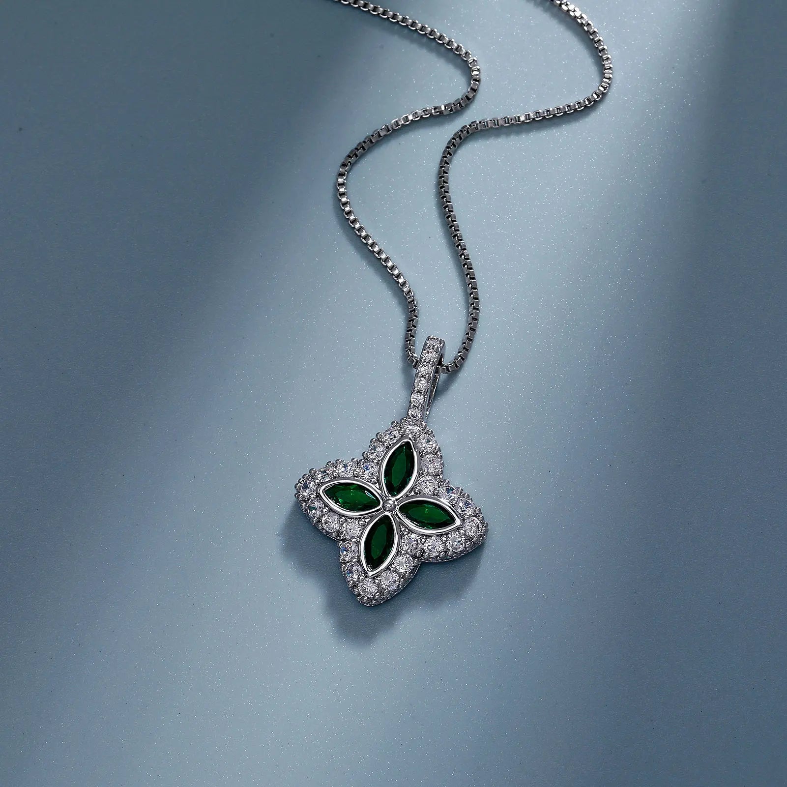 Silver necklace with a green gemstone pendant on a blue background