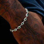 Silver bracelet with green gemstones on a tattooed arm